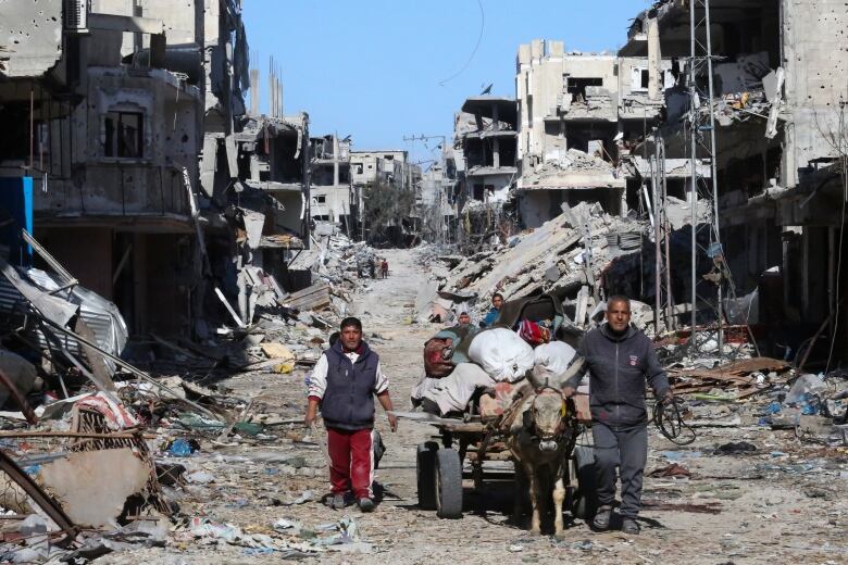 Palestinians walk through the destruction left by the Israeli offensive on Khan Younis, Gaza Strip, Friday, March 8, 2024.