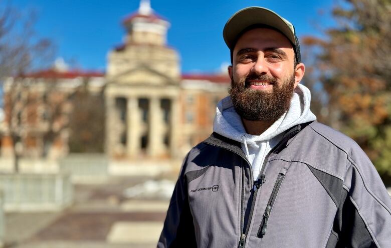 A man with a beard and hat, smiling.