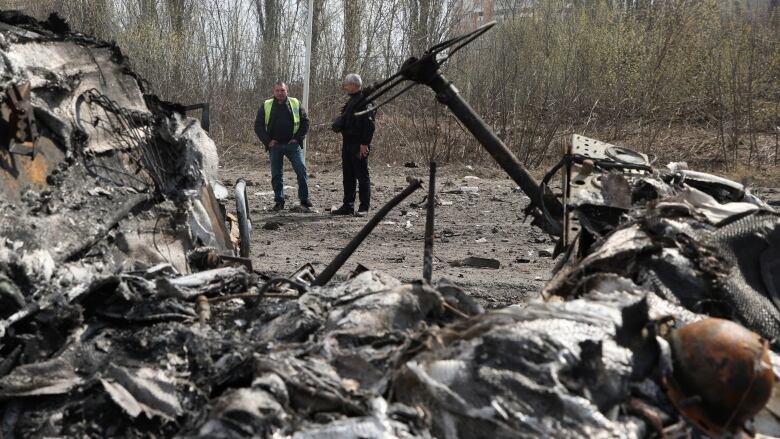 Two men stand near the remnants of a car body that was destroyed amid Russian missile strikes on Kharkiv, Ukraine. 