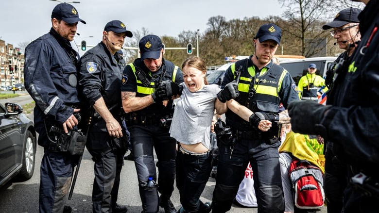 A person shouts as they are dragged away by police officers.