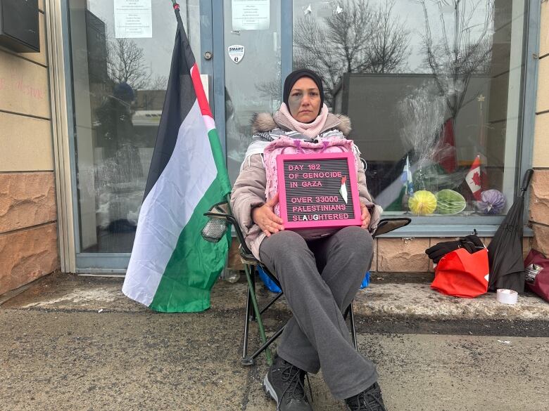 A woman sitting down with a protest sign. 