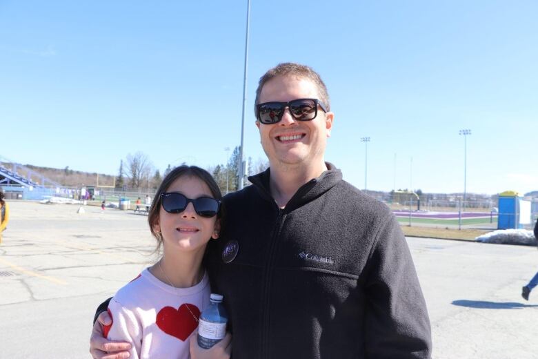 Smiling man with girl beside him.