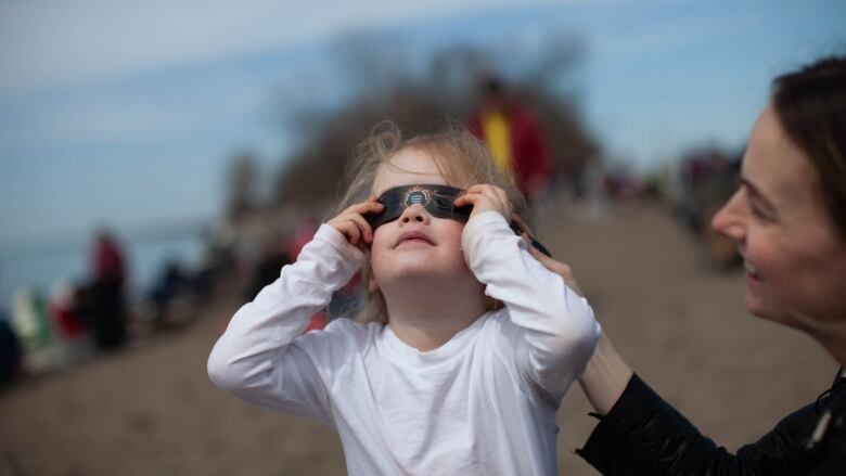 A young girl stands with a parent