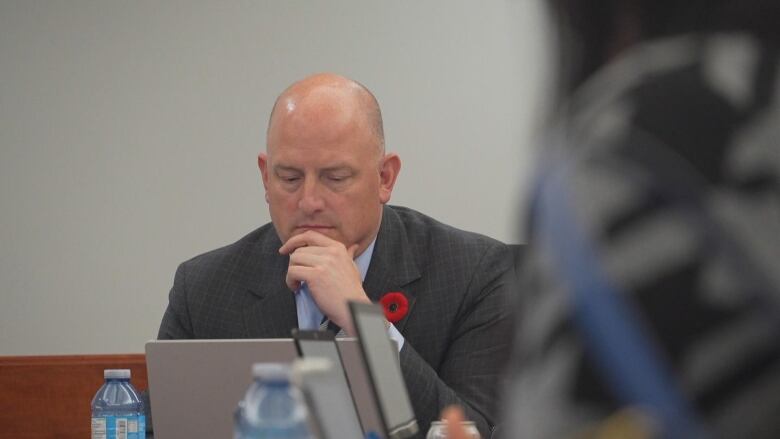 A man in a suit sits at a meeting table.