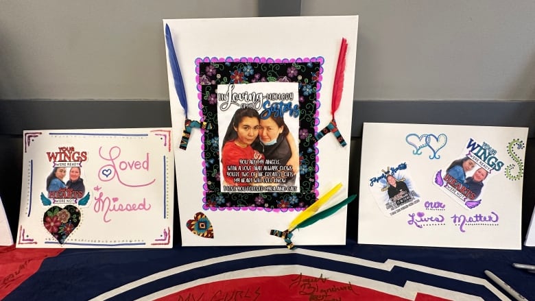 Hand-made cards and posters with photos of two women are displayed on a table.