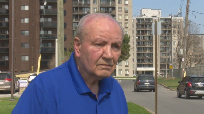 A senior-age man stands next to a short street.