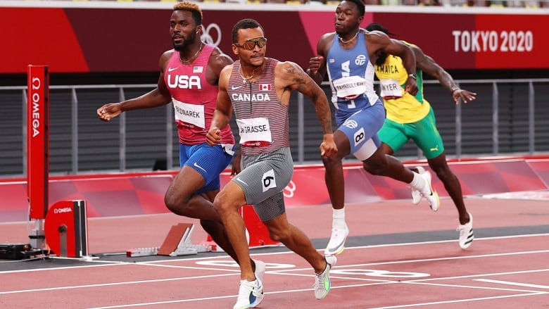 Men's sprinters cross the finish line at the Olympics.