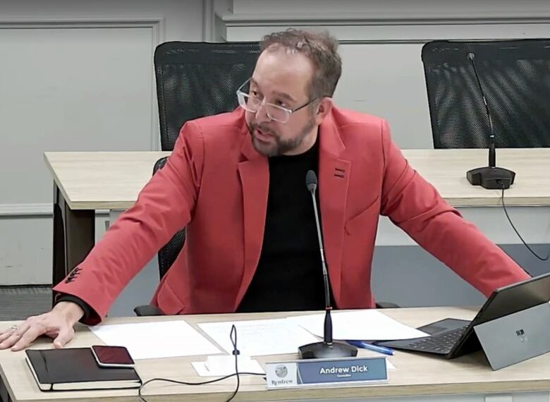 A township councillor speaks at his seat in council chambers during a public meeting.