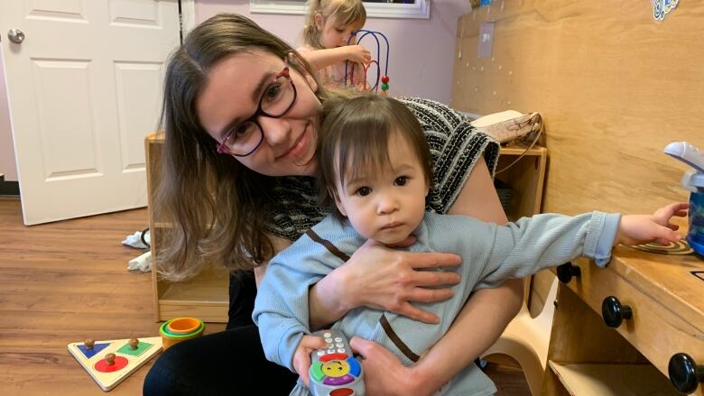 A mother hugs her toddler while playing together at a daycare. 