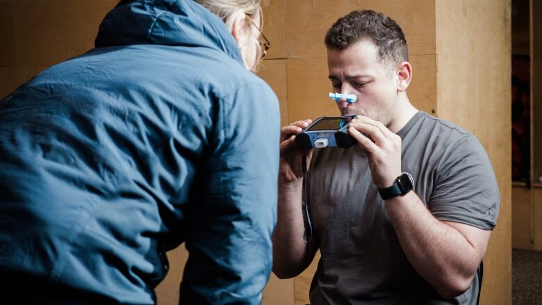 A researcher teaching a wildfire firefighter volunteer to breath into an apparatus to collect respiratory data. 