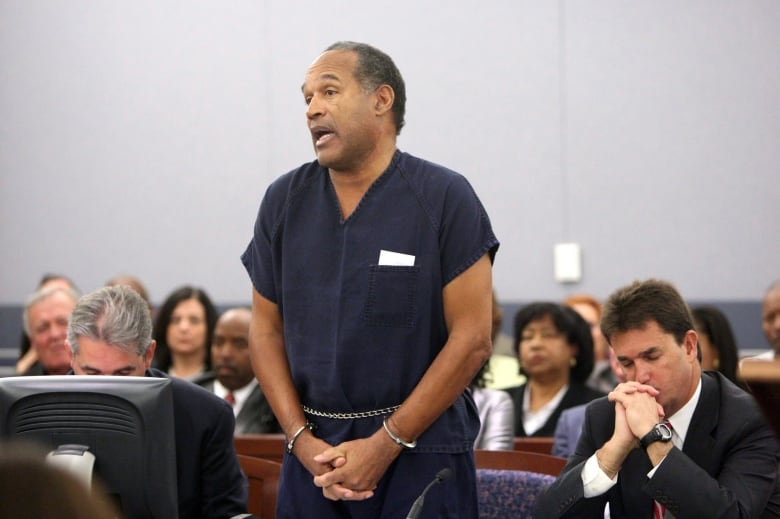 Handcuffed, a Black man speaks in a courtroom during his sentencing.