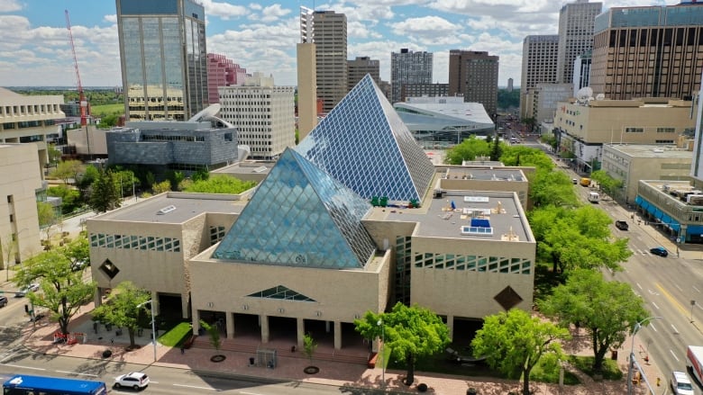 Aerial shot of a building with two glass pyramid-like-structures jutting out the top. 