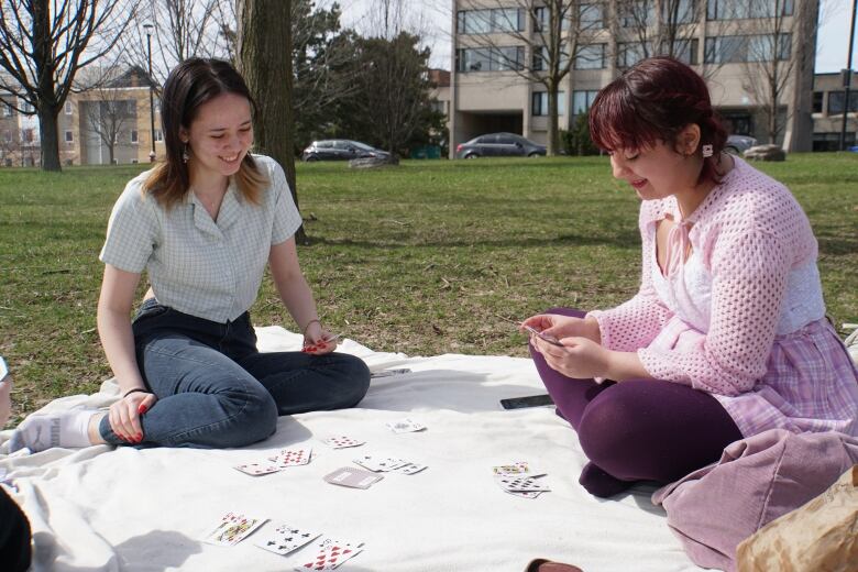 Theatre students Lia Germansen, left, and Leila Tamim, right, pass the time by playing cards will their in-person classes are paused.