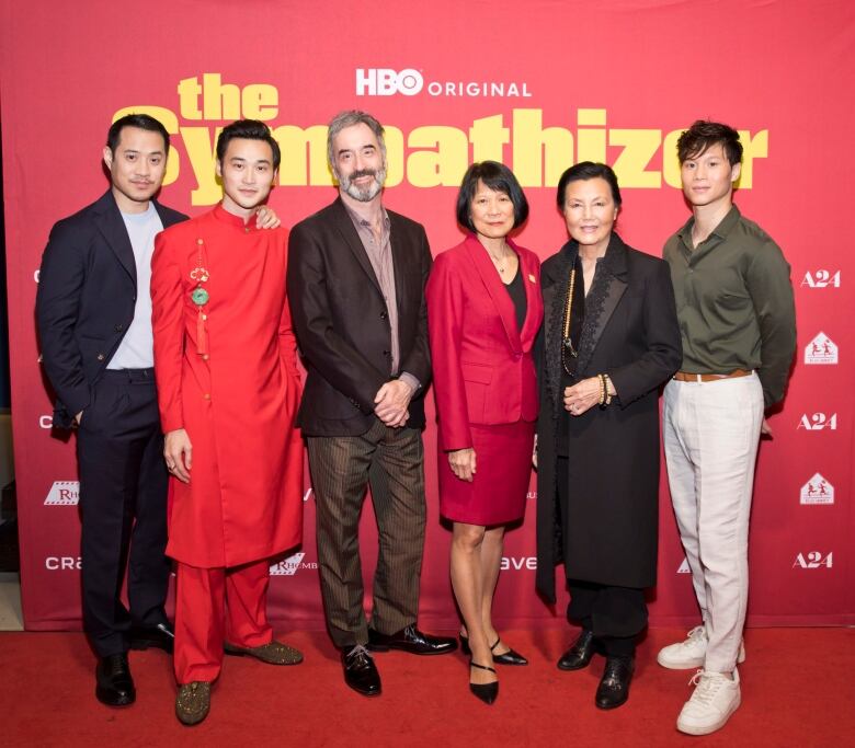 Six people stand in front of a photowall which bears the words The Sympathizer