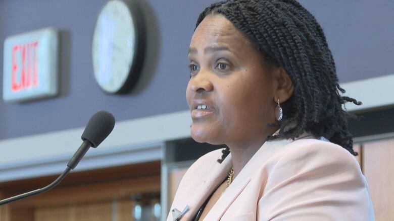 A Rwandan survivor stands at a podium giving a keynote speech.