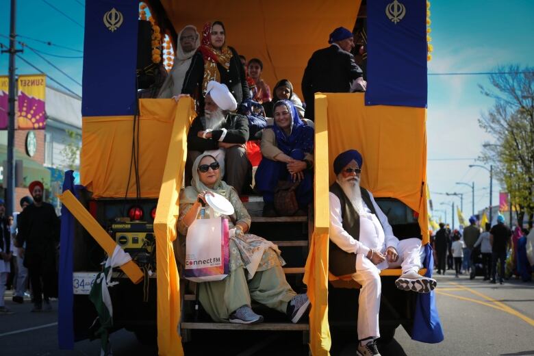 A number of people smile while seated on a parade float.