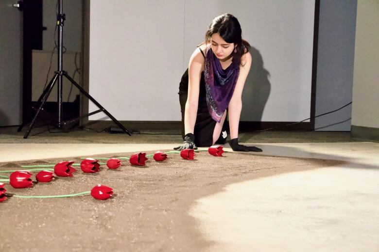 A young woman lays out red ceramic tulips onto the floor.