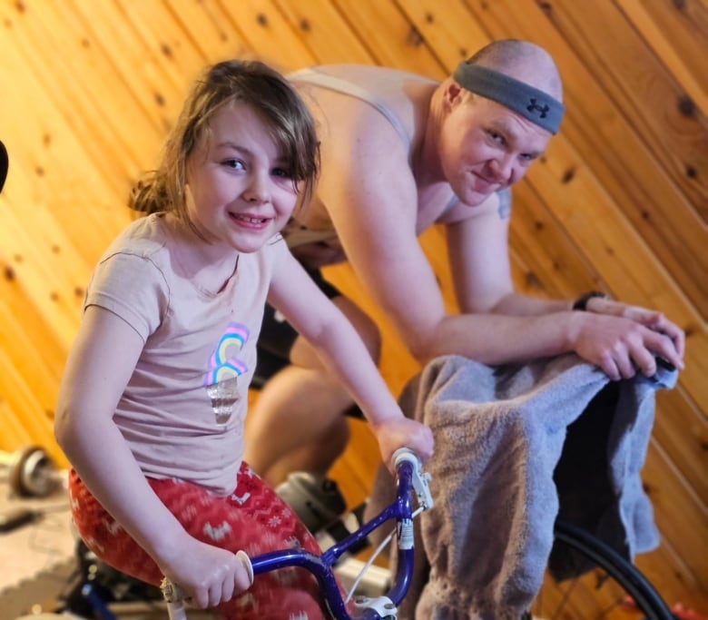 Robert Kirschman, who is training for a triathlon while battling a rare form of cancer, says his daughter, Aubrey, often keeps him company on his stationary bike rides.