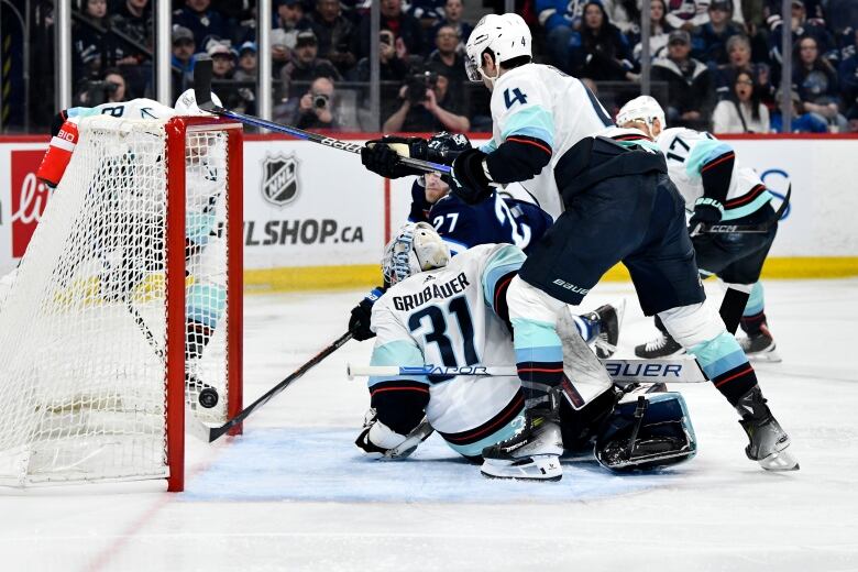 Seattle's goalie looks behind him, as Winnipeg's Nikolaj Ehlers tucks the puck into the net.