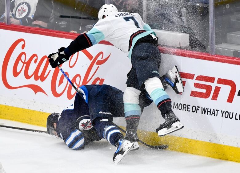 A Seattle player hits a Winnipeg player along the boards.