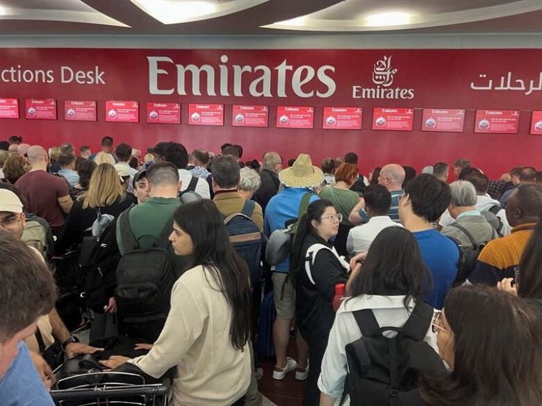 People wait at a flight connection desk at Dubai International Airport.