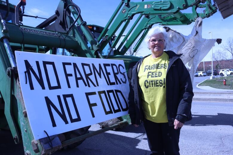 Woman stands in front of her John Deere tractor during protest