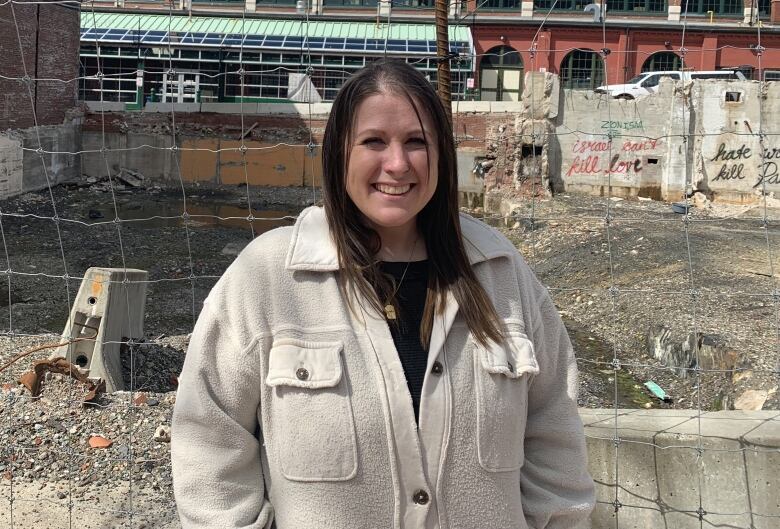 Woman standing in front of empty construction lot.