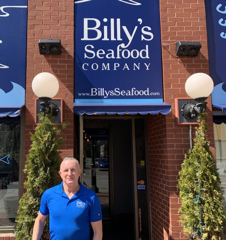 Man standing in front of his restaurant smiling at camera.