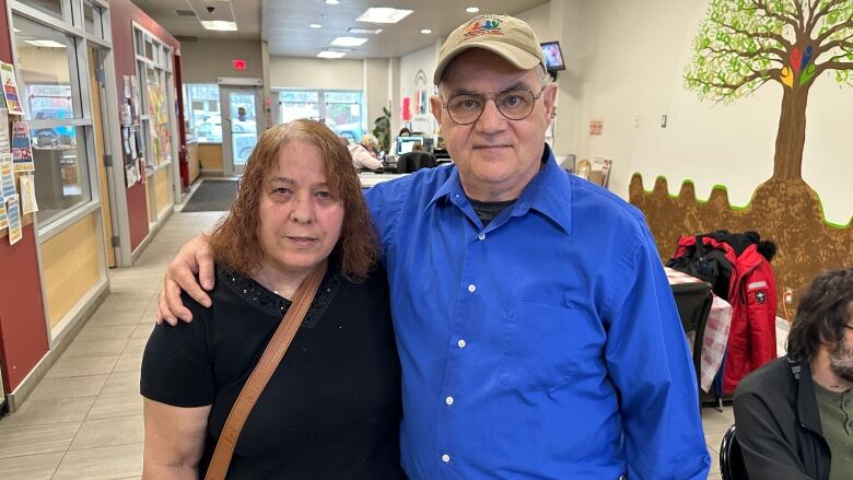 A woman in a black shirt and a man wearing a blue shirt and baseball cap.