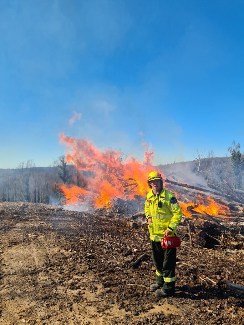 A man poses in front of a fire.