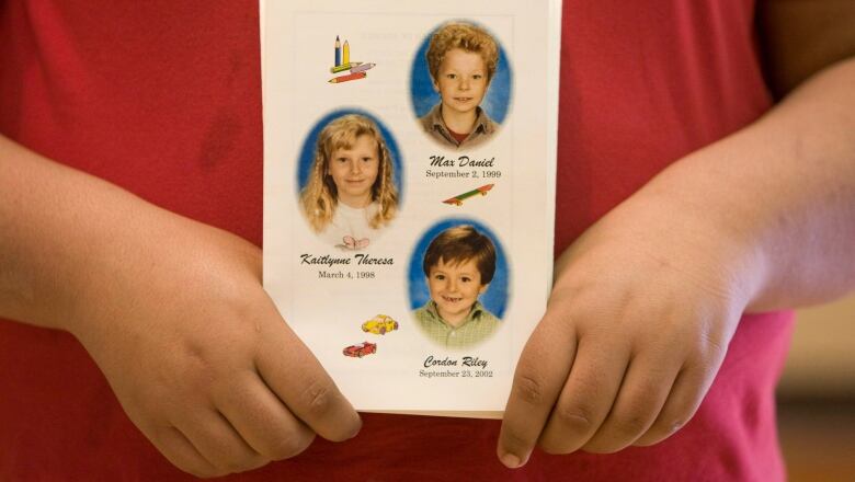 A mourner holds a program showing the pictures of Max, Kaitlynne and Cordon Schoenborn during a public memorial in Merritt, B.C. Sunday, April 27, 2008.