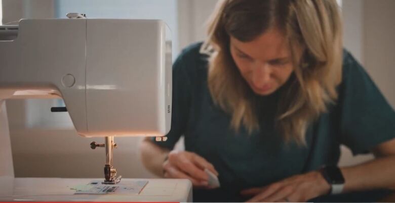 Woman works at sewing machine.