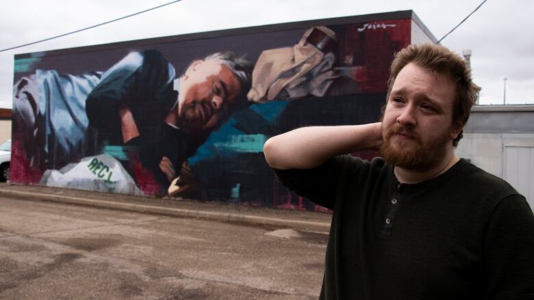 A man stands by an art mural.