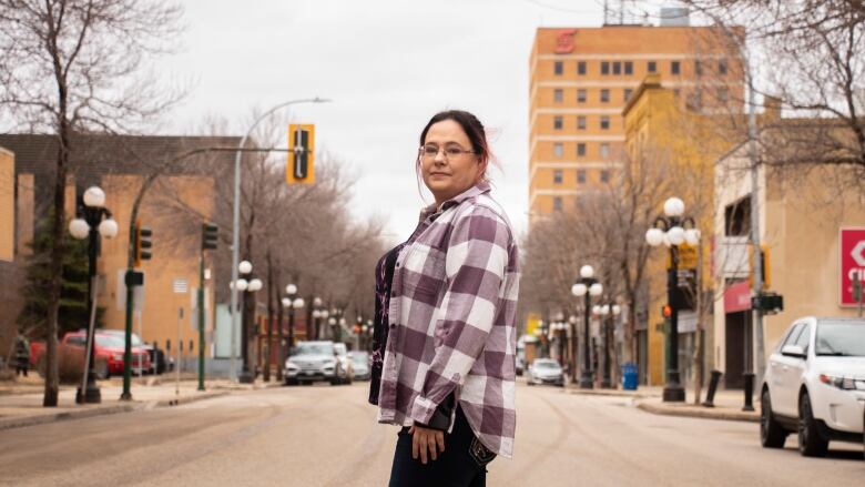 A woman stands on a downtown street.