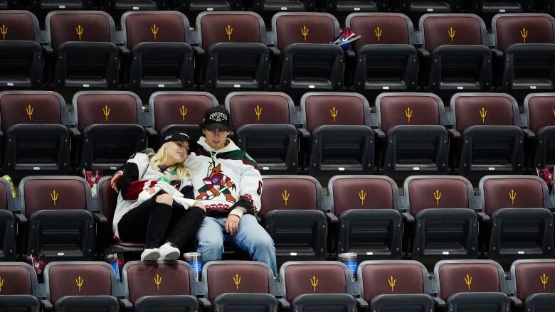 Two people sit in an empty arena