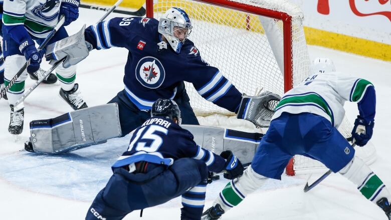 Winnipeg's goalie stretches out his glove hand to make a save against a Vancouver player.