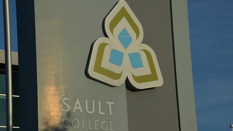 A flower logo and the words 'Sault College' on a sign 