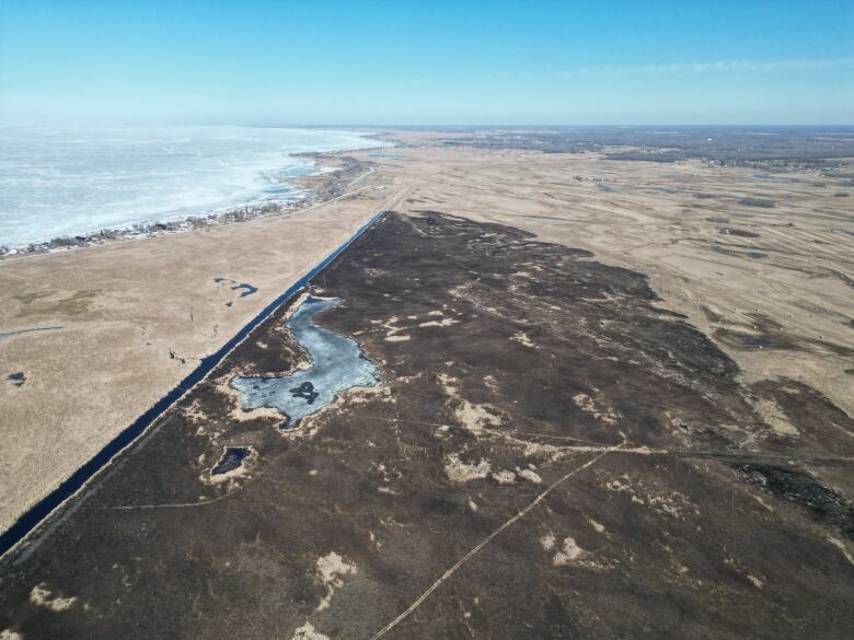 An aerial photo shows a big patch of burned marshland within meters of lakeside homes.