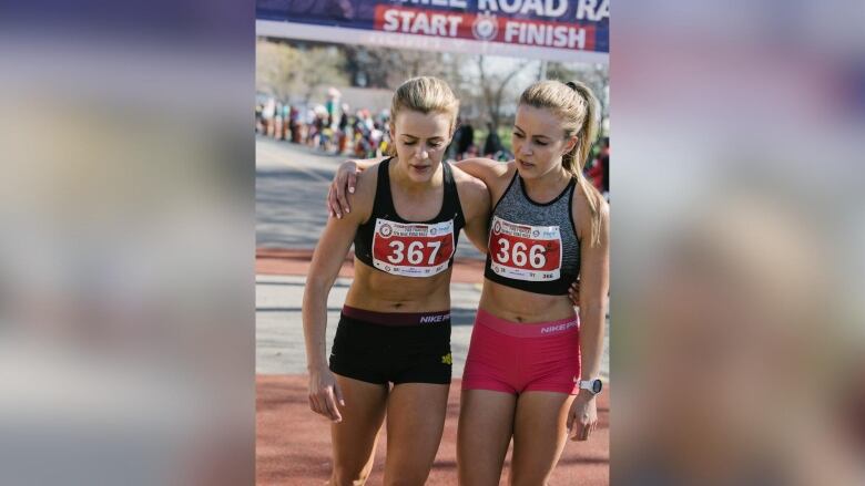 Two people with their arms around each other at the end of a running race. 