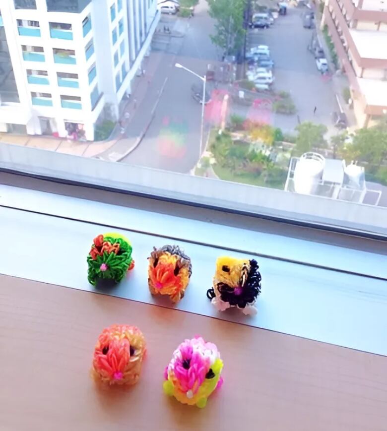 Five rainbow looms are shown on a windowledge.