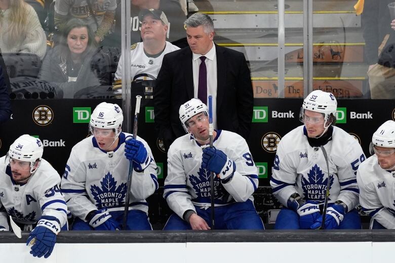 Hockey players are seen seated on the bench.