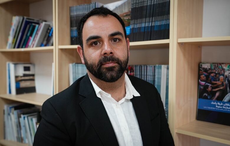 A person stands in front of bookshelves.