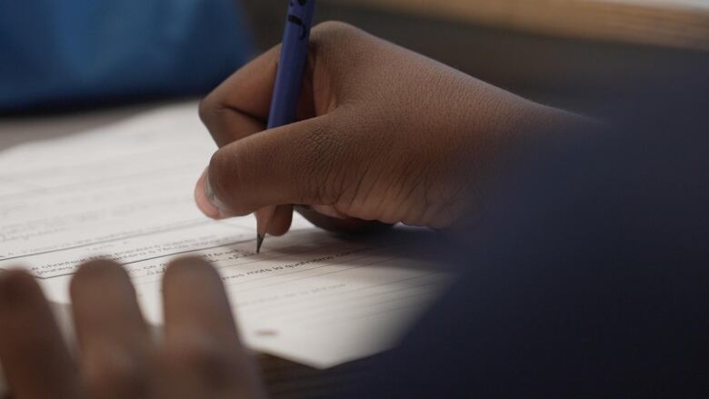 A child's hands writing on a sheet of paper