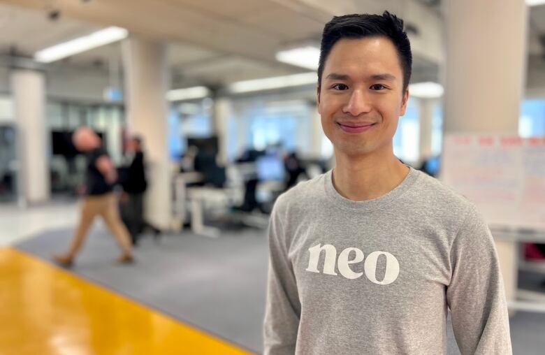 A man in a grey Neo Financial shirt stands in an office.