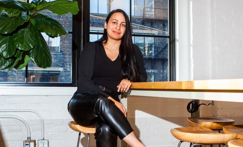 A woman poses at a wooden table.