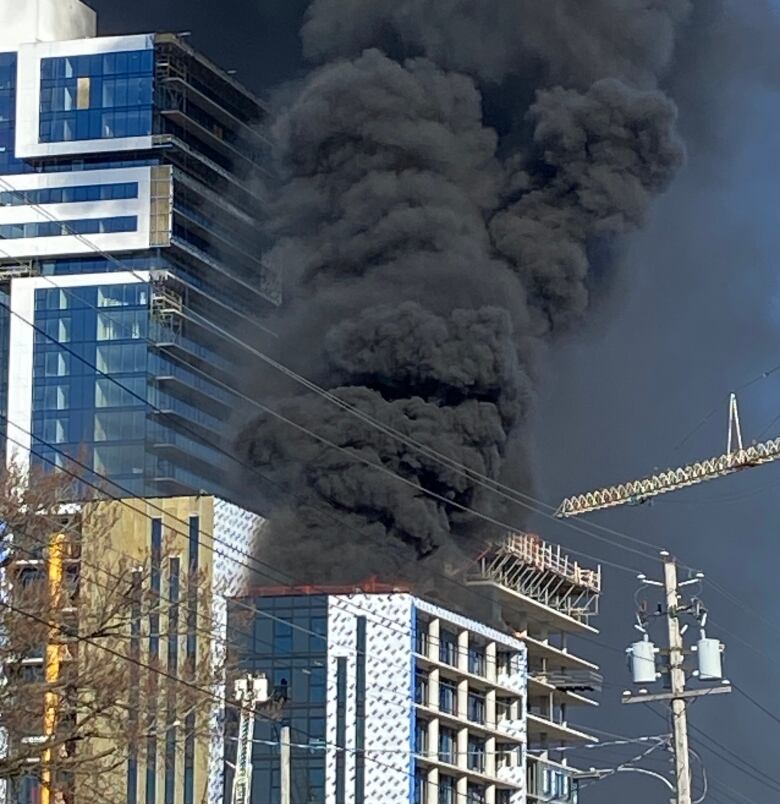 Large plumes of back smoke billow from an under construction building.