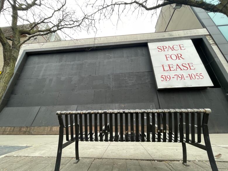 A bench in front of a boarded-up building