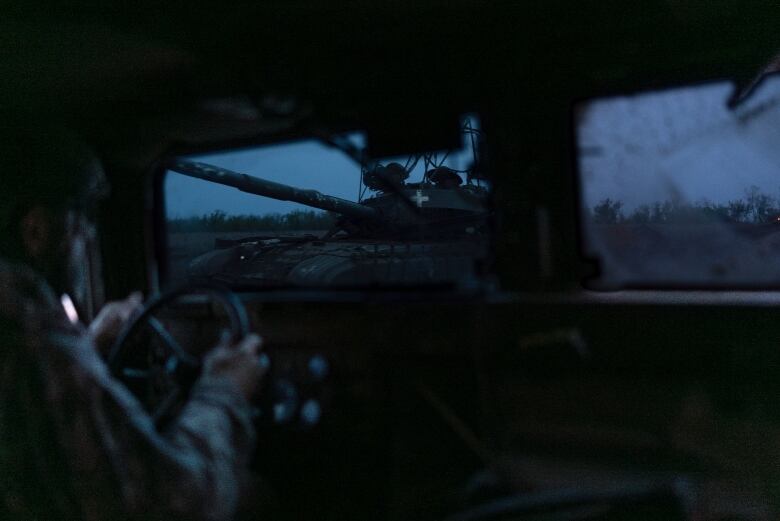 A Ukrainian soldier drives near a tank in a front-line position near Bakhmut, Ukraine.