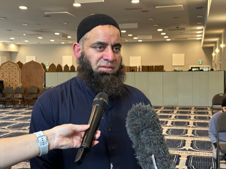 a man speaks to microphones inside a mosque