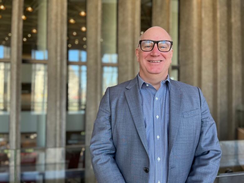 A man wearing glasses and a suit poses for a photo.